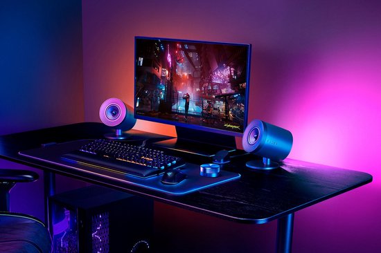 Gaming bureau met Razer speakers, toetsenbord, muis en monitor met paars/blauw licht.