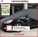 Zwarte auto met grijze, extreem rekbare autohoes van elastisch materiaal, in een garage.