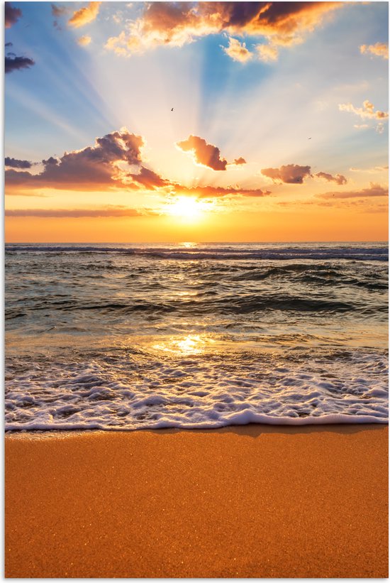 Zonsondergang boven de zee met gouden strand, zonnestralen breken door wolken.
