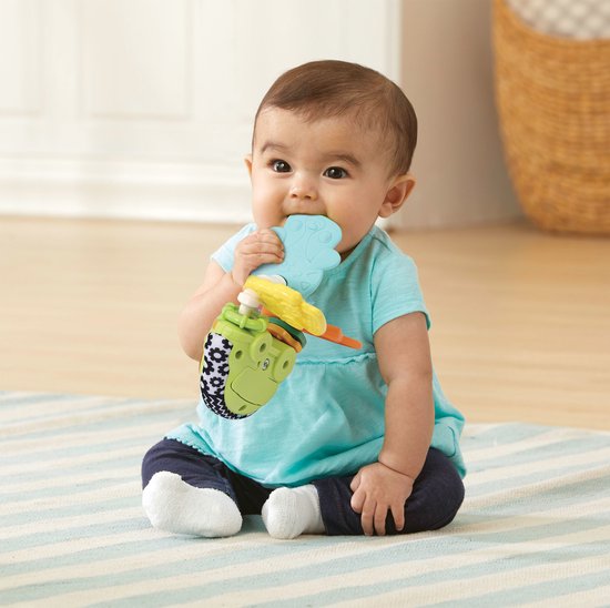 Baby in blauw shirtje bijt op lichtblauwe en gele onderdelen van de VTech rammelsleutel.