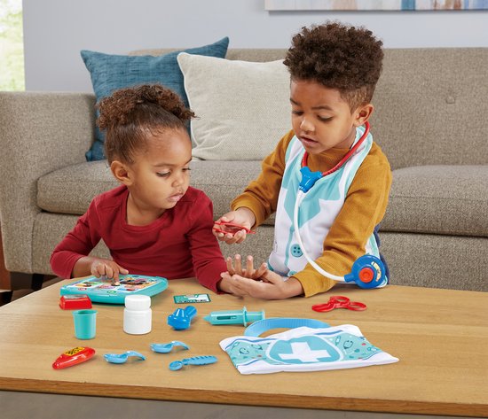 Twee kinderen spelen met speelgoeddoktersbenodigdheden op de vloer, waaronder een tablet en een dokterskoffer.