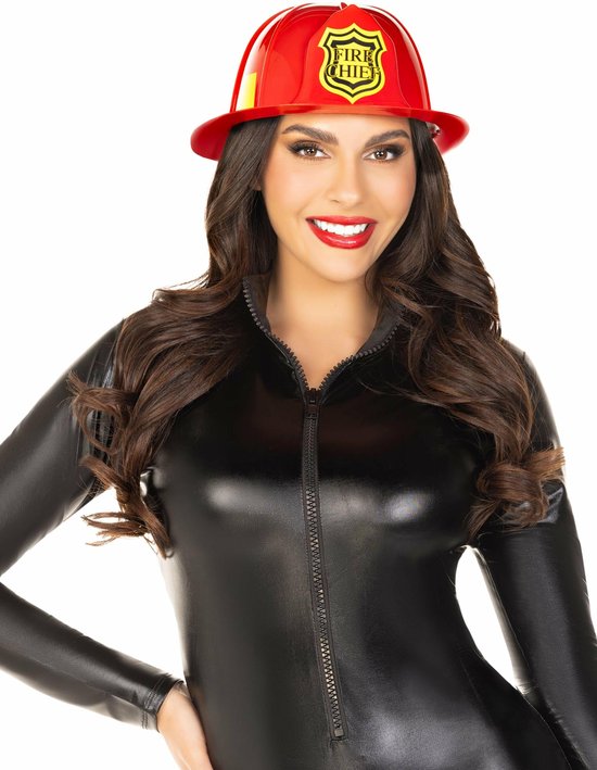 Vrouw met donker haar, draagt een rode brandweerhelm met 'FIRE CHIEF' embleem, en een zwarte nauwsluitende outfit.