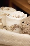 Rol van witte hydrofiele doek met bruine print van bloemen en takjes, naast een teddybeer.
