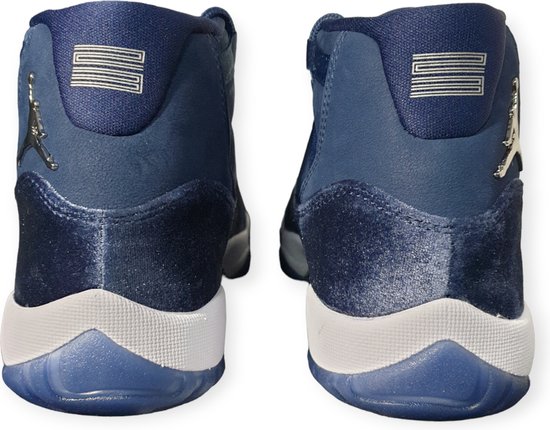 Achterkant van twee donkerblauwe mid-top sneakers met witte zolen en zilveren Jumpman-logo's.