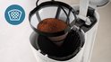 Gros plan du panier-filtre avec du café moulu dans une cafetière Philips blanche.