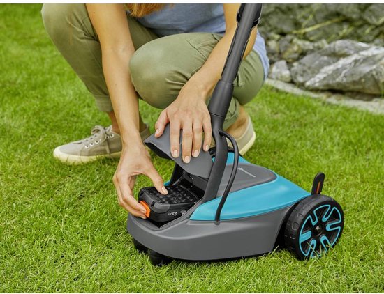 Hand die een batterij uit het batterijvak van de blauw-grijze grastrimmer haalt.