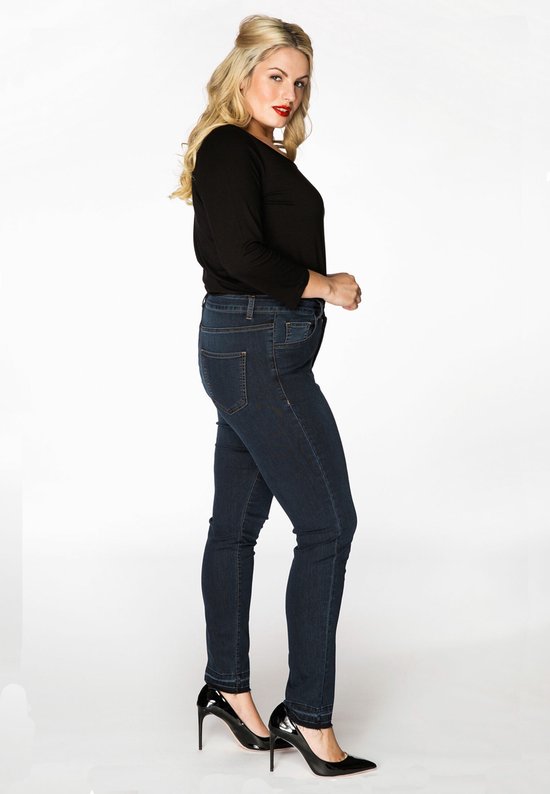 Model van opzij met donkerblauwe spijkerbroek met hoge taille, zwart shirt en zwarte hakken.