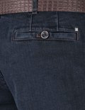 Donkerblauwe jeans met bruine stiksels, een knoop op de achterzak en een riem met krokodillenprint.