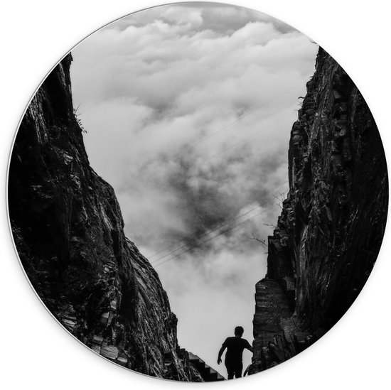 WallClassics - PVC Schuimplaat Muurcirkel - Man tussen Rotsen boven Wolken in Zwart-wit - 70x70 cm Foto op Muurcirkel (met ophangsysteem)