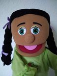Jonge poppenhoofd met grote groene ogen, zwarte vlechten en paarse strikjes, groen shirt.