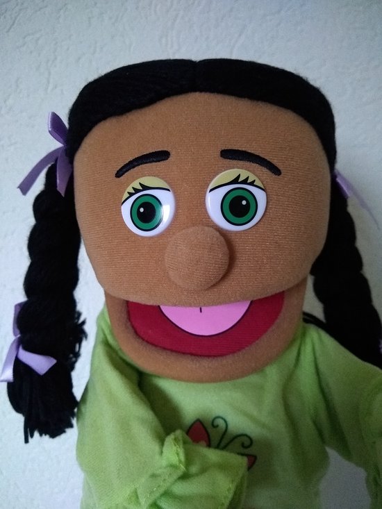 Jonge poppenhoofd met grote groene ogen, zwarte vlechten en paarse strikjes, groen shirt.