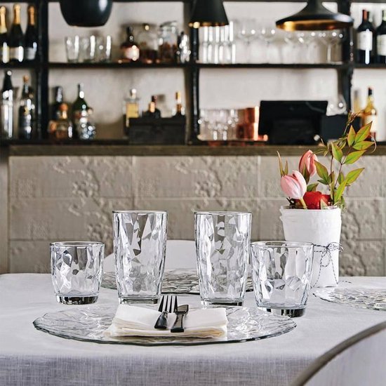 Quatre verres, deux hauts et deux bas, sur une table dressée.