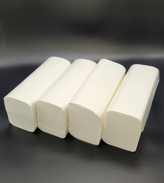 Vier pakken witte papieren handdoekjes op een rij op een donkere achtergrond, deels zichtbaar in plastic.