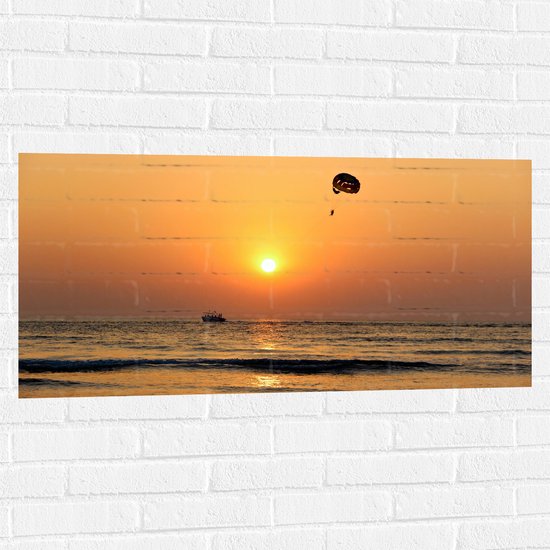 WallClassics - Muursticker - Parasailen bij Zonsondergang Boven de Zee - 100x50 cm Foto op Muursticker