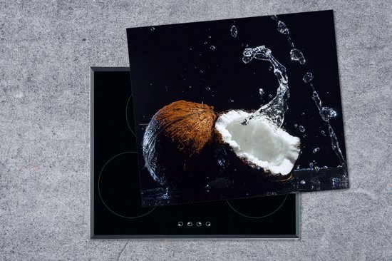Een kokosnoot met waterplassen op een zwarte achtergrond, geplaatst op een inductiekookplaat.