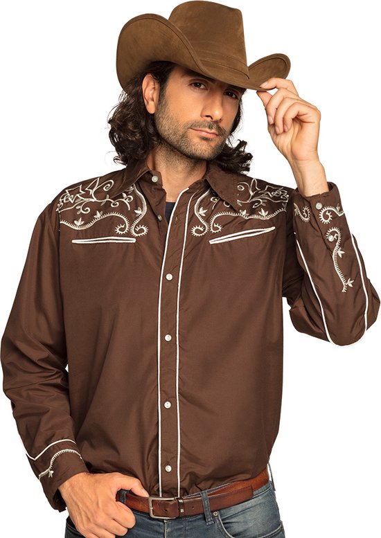 Man in bruin western overhemd met witte borduursels, een cowboyhoed en spijkerbroek.
