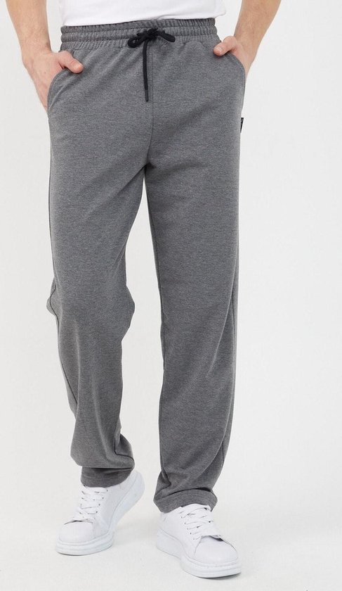 Man met handen in zakken van donkergrijze joggingbroek met zwart trekkoord.