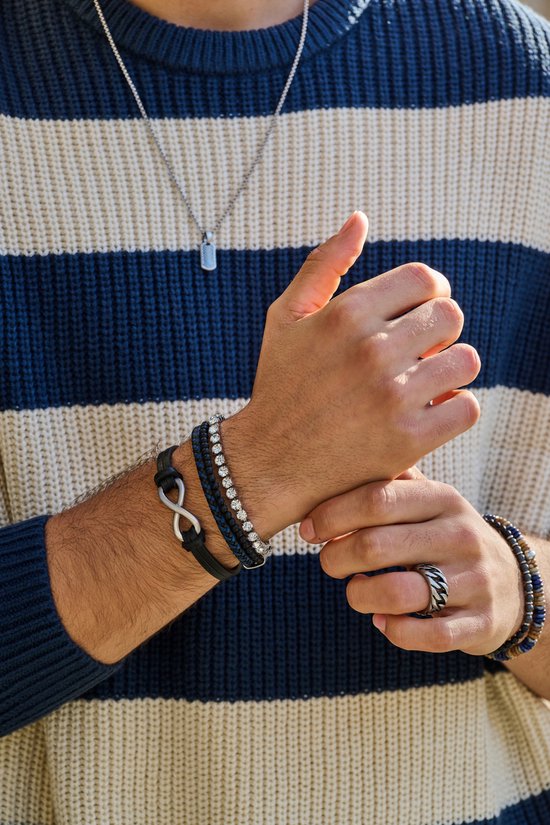 Man met donkerbruine leren armband met infinity symbool en blauw-wit gestreepte trui.
