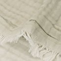 Detail van een groene mousseline deken met rafels en textuur.