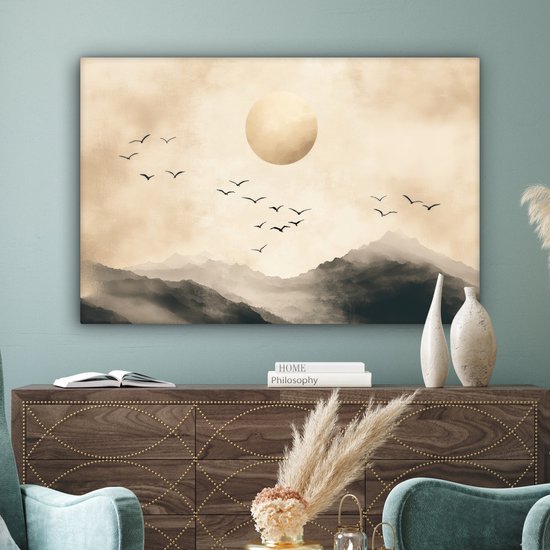Toile paysage abstrait avec montagnes, grand cercle doré et oiseaux en vol, accrochée au-dessus d'une commode.