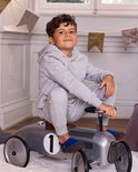 Jongen in grijze joggingbroek op een speelgoedauto, dragend blauw-grijze Cosyshoe huissokken.