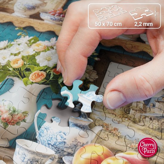 Een hand legt een puzzelstukje met een blauw-wit porseleinen patroon op een grotere puzzel van servies, bloemen en fruit.