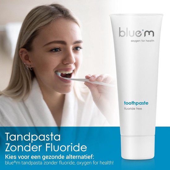 Vrouw in badjas poetst tanden met witte tandenborstel. Naast een witte tube tandpasta met blauwe tekst.