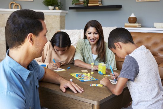 Een gezin speelt Pictionary aan een tafel. Een vader, moeder en twee kinderen.