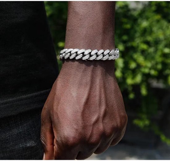 Zilverkleurige gourmette schakelarmband met zirkonia's gedragen om een donkere pols.