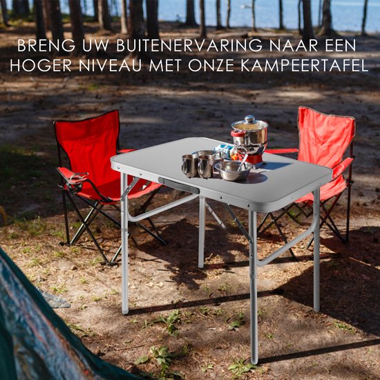 Zilverkleurige campingtafel met twee rode stoelen in een bosrijke omgeving, met tekst 'BRENG UW BUITENervaring NAAR EEN HOGER NIVEAU MET ONZE KAMPEERTAFEL'.