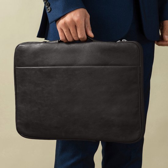 Man in blauw pak houdt een zwarte laptoptas met handvat vast.