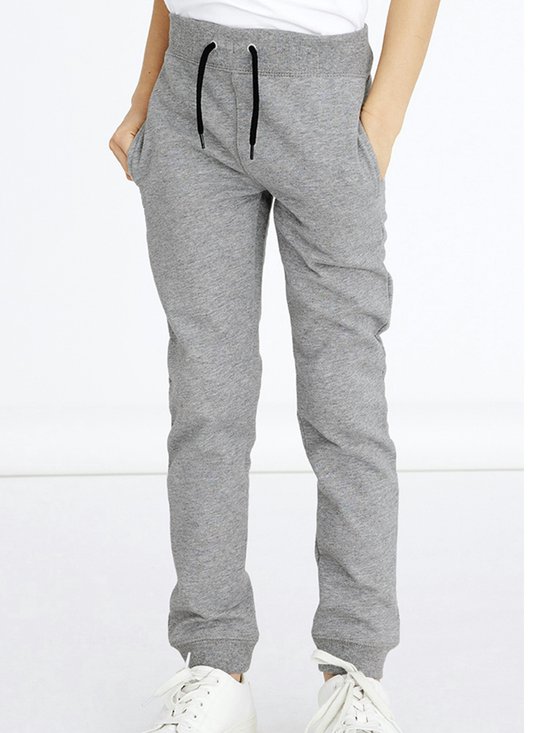 Jongere met grijze joggingbroek met zwarte veter en witte sneakers.