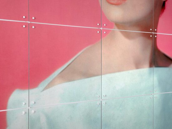 Une femme portant du rouge à lèvres, son épaule et son cou visibles, porte un haut bleu pâle épaules dénudées sur fond rose.