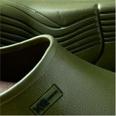 Close-up van een groene XQ Footwear klomp, met focus op de textuur van het materiaal en het XQ Footwear logo.