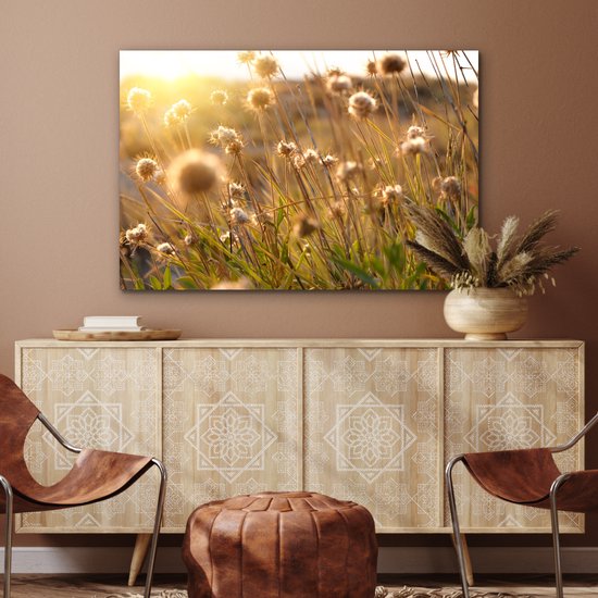 Une peinture de fleurs séchées sous la lumière dorée du soleil, au-dessus d'une armoire en bois décorée.
