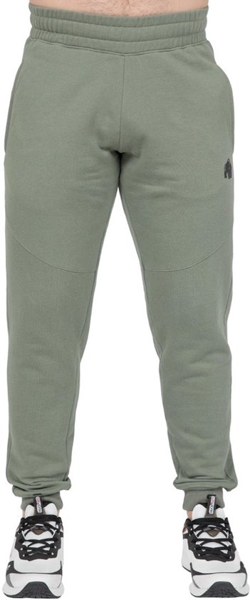 Man in groene joggingbroek met elastische tailleband en zwarte sneakers.