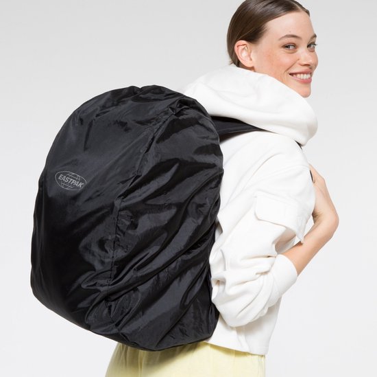Vrouw met witte hoodie draagt zwarte Eastpak regenhoes over rugzak.
