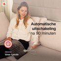 Vrouw met verwarmingskussen op schoot, met tekst 'Automatische uitschakeling na 90 minuten'.