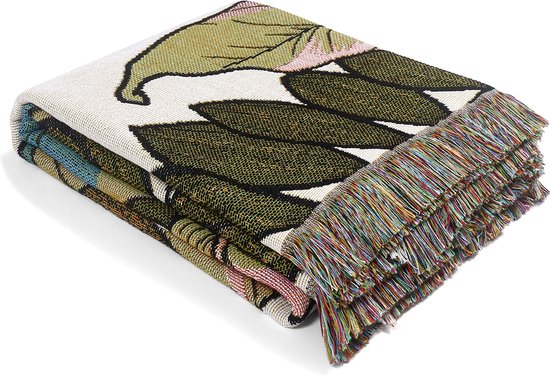 Beige deken met grote, groene bladeren en franjes. De deken is opgevouwen.