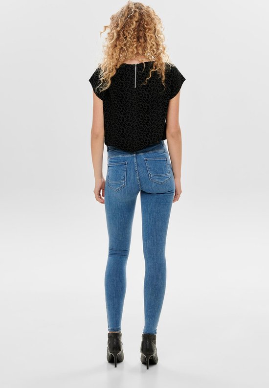 Model in lichte spijkerbroek en zwarte top met luipaardprint, van achteren gezien.