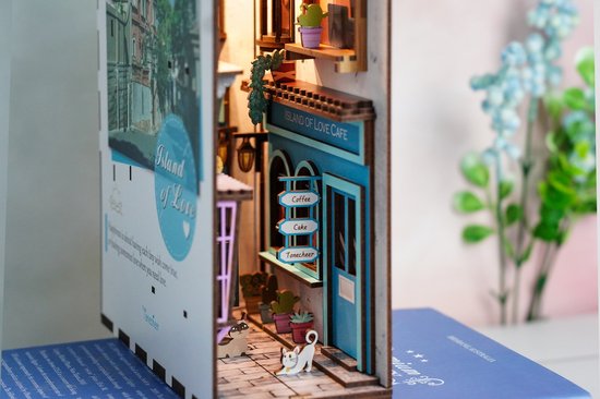 Detail van de houten boekensteun met miniatuur café, straatscène, slapende kat en bloemen.