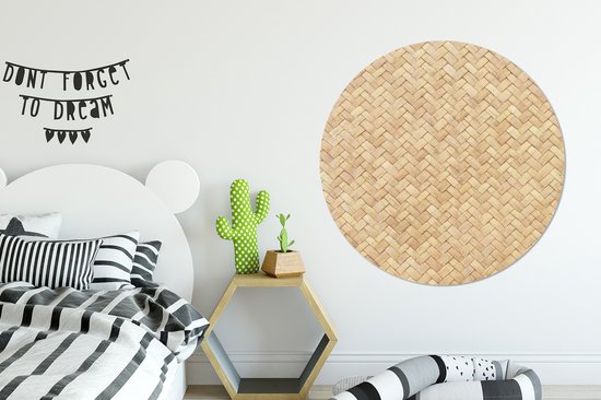 Décoration murale ronde imprimé rotin au-dessus d'un lit avec une literie à rayures noires et blanches.