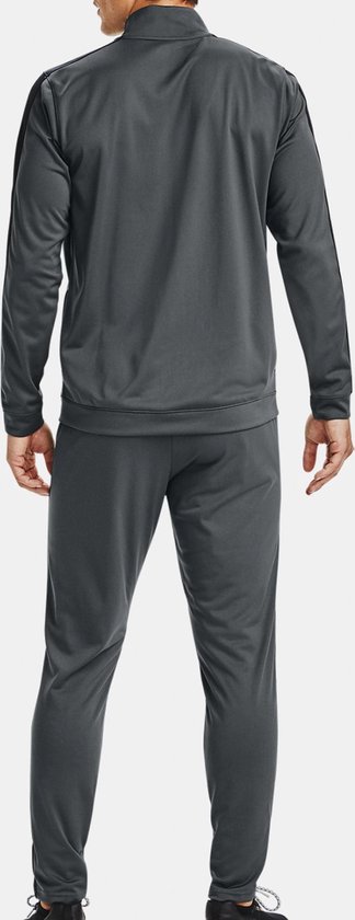 Achterkant van een man met een grijs trainingspak van Under Armour. Zwarte strepen op de mouwen en zijkanten van de broek.