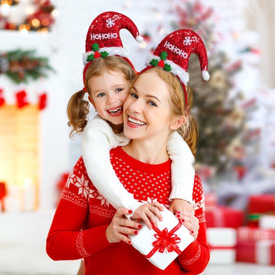 Een moeder en dochter omhelzen elkaar, beide met kerstmutsen met 'HO HO HO' en glitters.