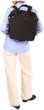 Vrouw met blauw shirt en beige broek, draagt een zwarte Hedgren rugzak.