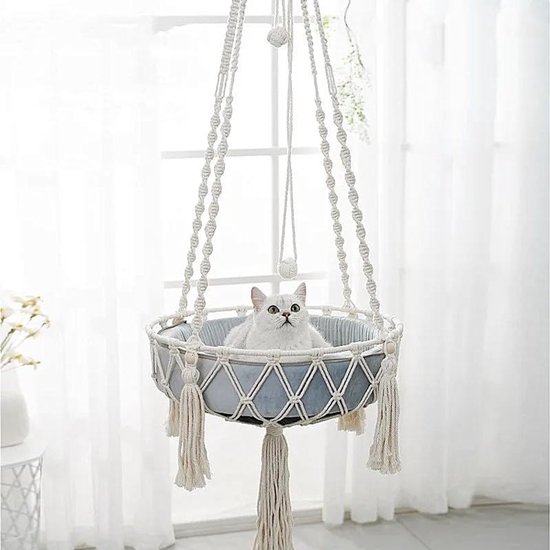 Witte macramé hangmat met grijze kussens, met een witte kat erin.