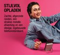 Vrouw met spijkerblouse laadt telefoon op met zilverkleurige magnetische powerbank.