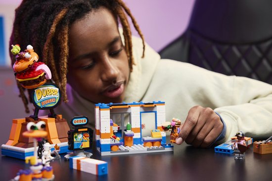 Garçon construisant un restaurant LEGO Fortnite avec la figurine Durrr Burger et d'autres personnages