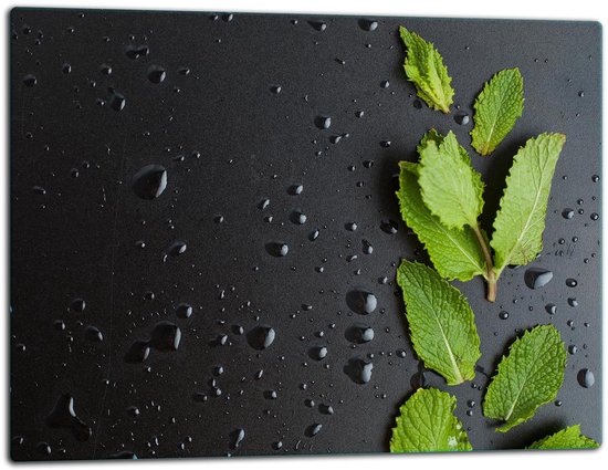 Planche à découper noire avec des gouttes d'eau et des feuilles de menthe fraîches.
