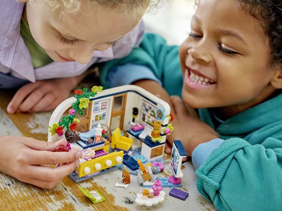 Twee kinderen kijken en spelen met een LEGO Friends kamer. Boven: een kamer met bed.